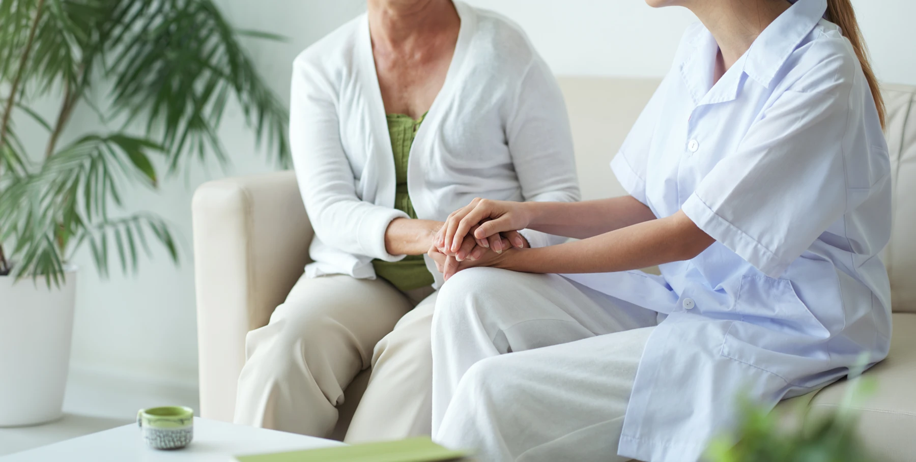 Patientin und Krankenschwester händehaltend